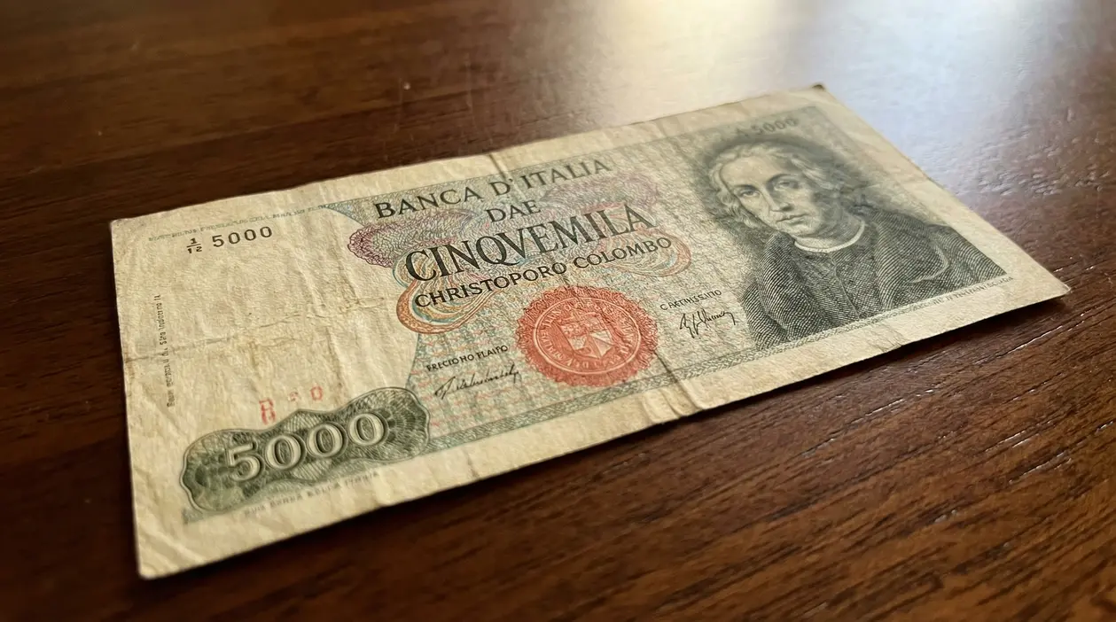 Banconota da 5000 lire con ritratto di Cristoforo Colombo su superficie in legno