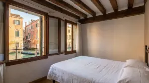 Camera con letto matrimoniale e vista su un canale di Venezia con edifici storici