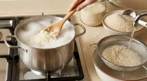 Pentola di riso che bolle e trabocca sul fornello, con riso sciacquato in un colino sotto acqua corrente