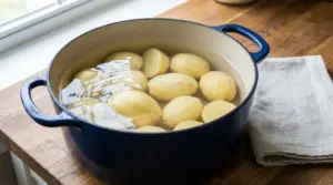Patate sbucciate immerse in acqua fredda dentro una pentola, pronte per la preparazione prima della cottura